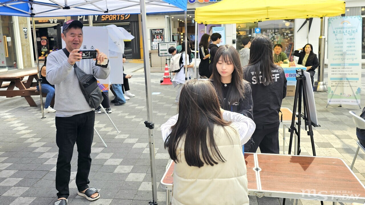 윤지현 씨가 딸 시하 양의 첫 투표 모습을 촬영하며 미소를 짓고 있다. (사진=한승미 기자)