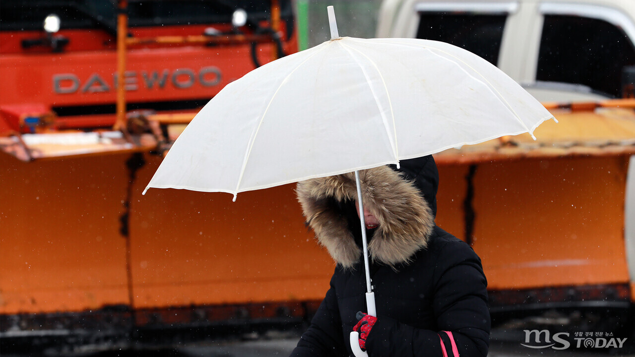 15일 오전부터 많은 양의 눈이 내리기 시작하자 한 시민이 우산을 들고 거리를 지나고 있다.