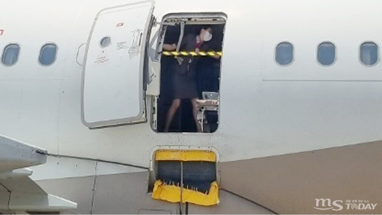 지난달 26일 제주공항에서 출발해 대구공항에 비상구 출입문이 열린 채 착륙한 항공기에서 한 승무원이 문에 안전바를 설치한 뒤 두 팔을 벌려 막고 있다. (사진=연합뉴스)