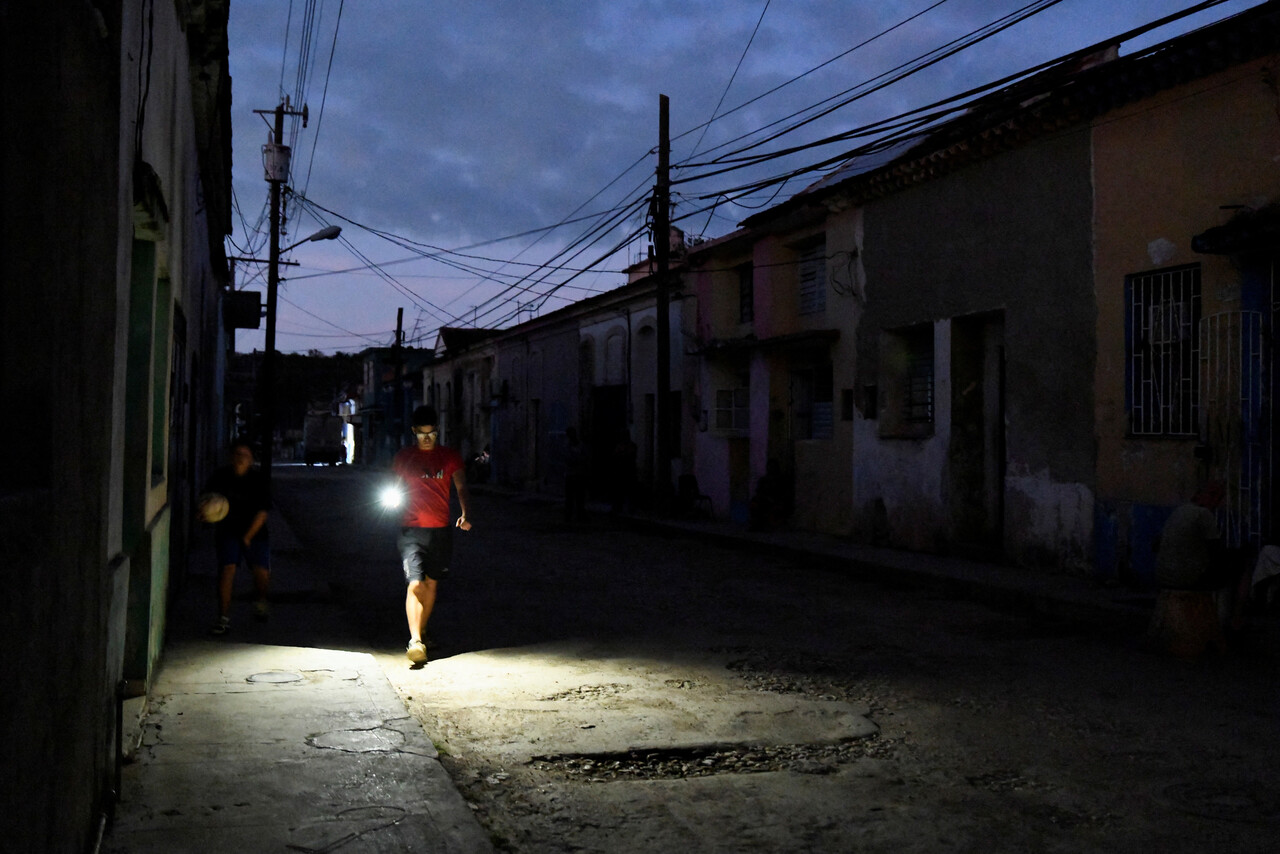 지난 8일(현지시간) 정전된 골목길을 휴대전화 불빛에 의지한 채 지나가는 쿠바 주민. 사진=연합뉴스