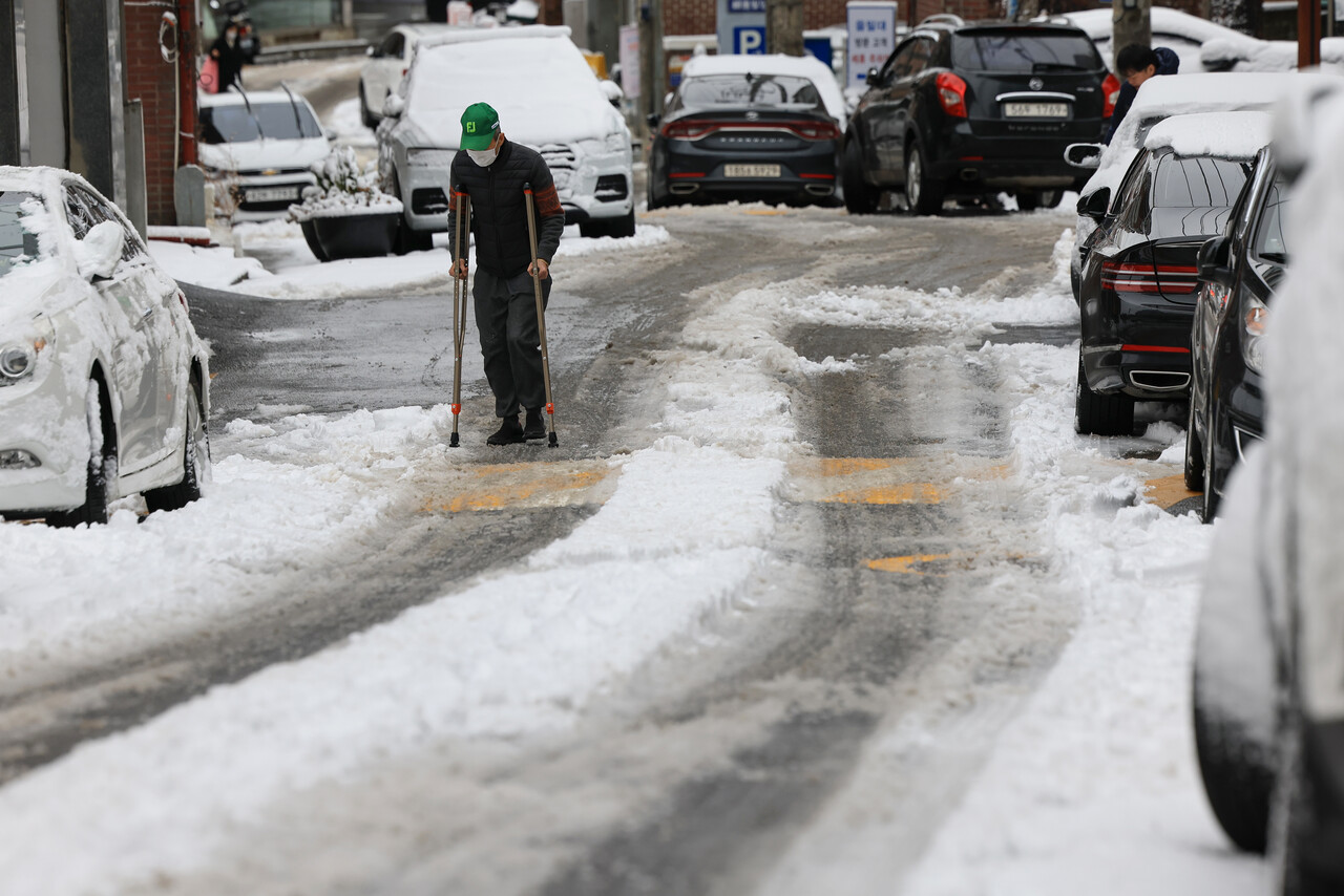 눈이 쌓인 서울 마포구의 한 도로에서 목발 짚은 시민이 걷고 있다. (사진=연합뉴스)